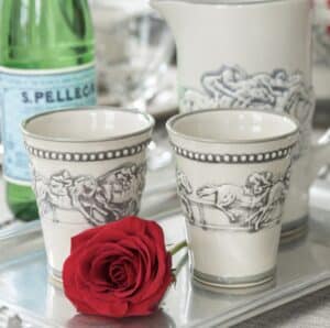 Two white mint julep cups and a picture with blue horse race pictures on a silver tray with a red rose.